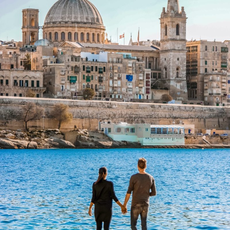 A couple on a city trip to Valletta Malta city Skyline, colorful house balcony Malta Valletta, panoramic view over Valletta Malta old town at sunset